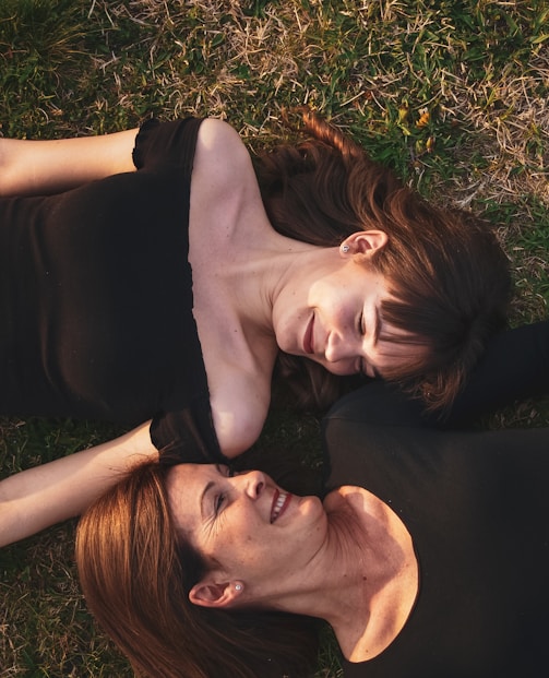 woman in black sleeveless dress lying on green grass field