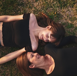 woman in black sleeveless dress lying on green grass field