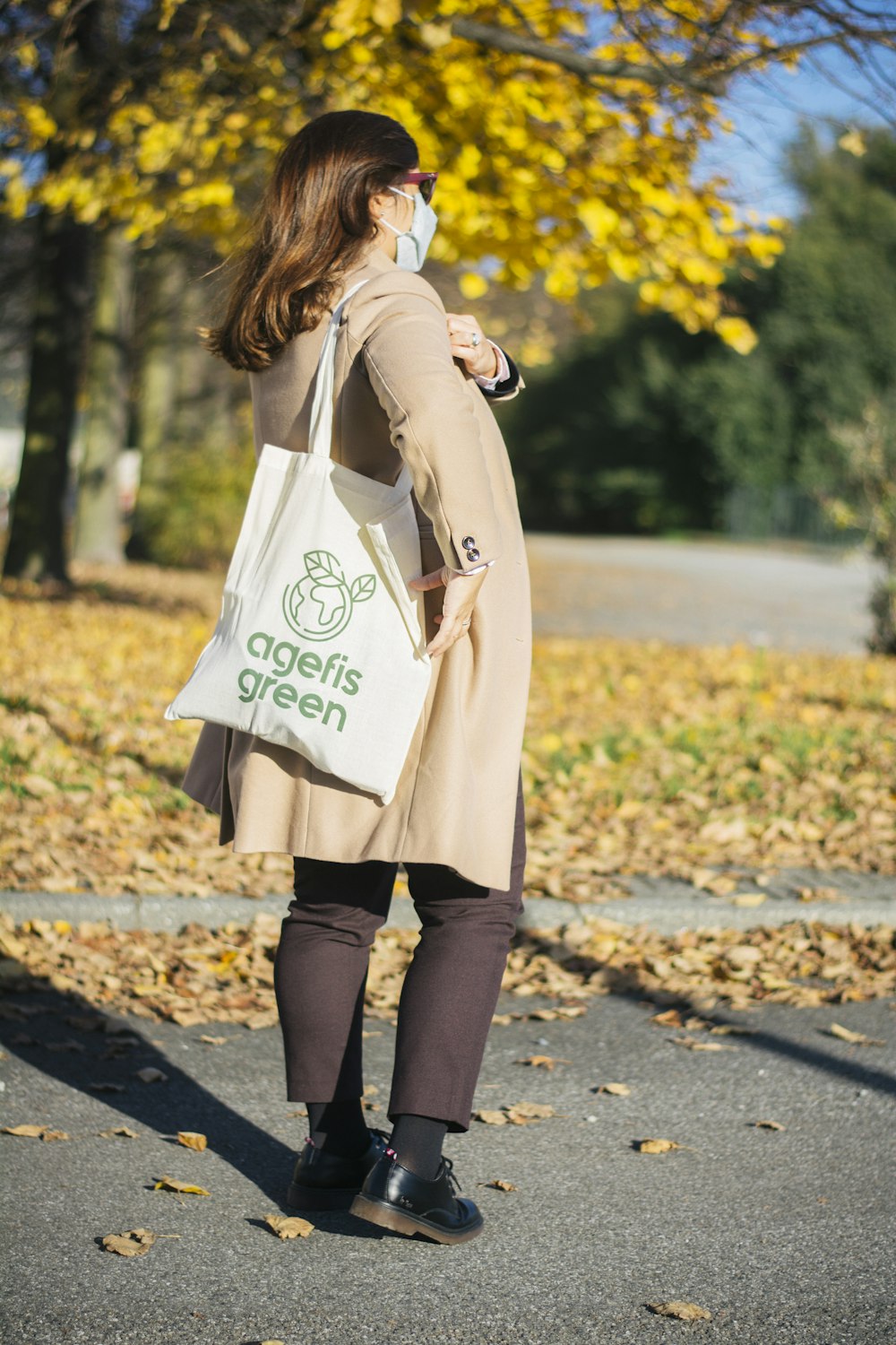 woman in beige coat and black pants carrying white tote bag