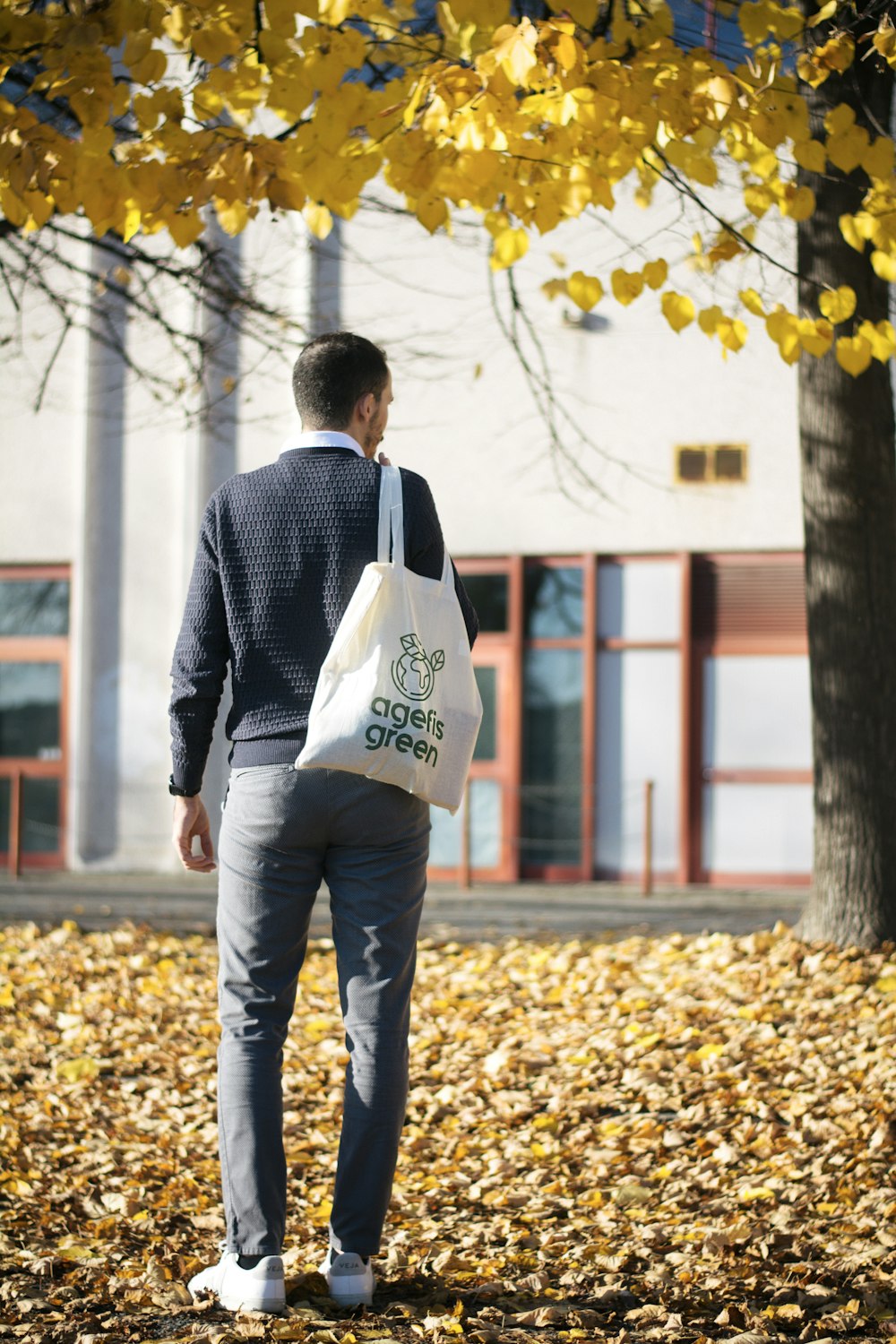 man in gray suit jacket and blue denim jeans standing on dried leaves during daytime