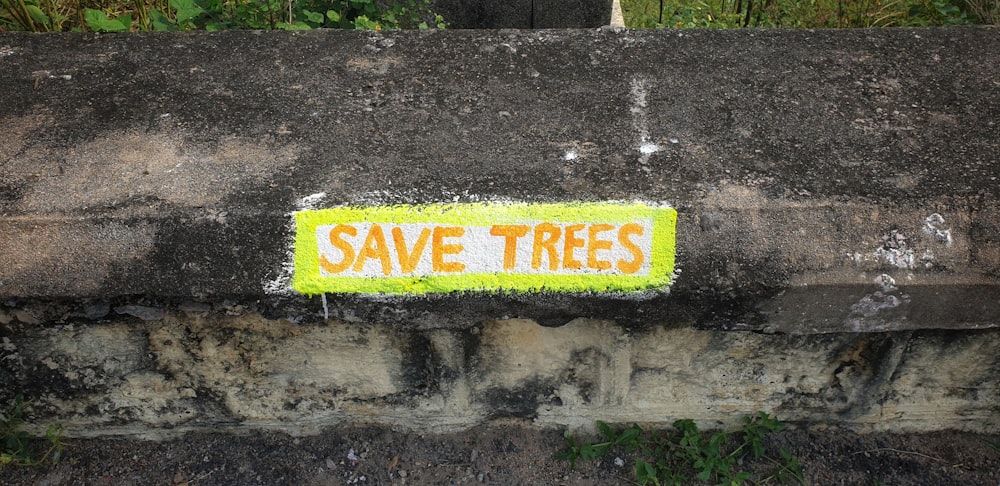a sign that says save trees on a stone wall
