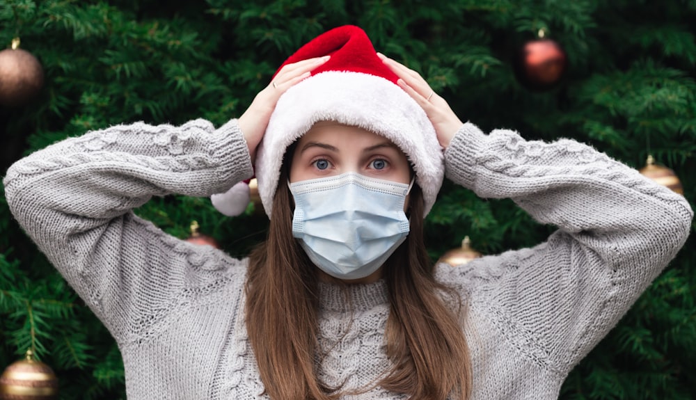 Frau in weißem Strickpullover mit weißer und roter Weihnachtsmannmütze