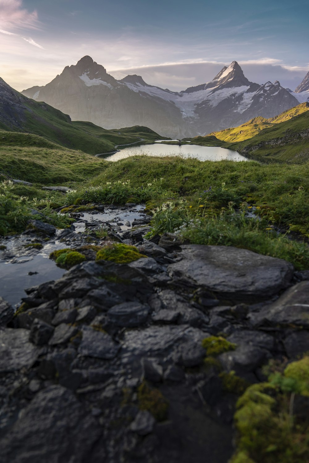 green grass and gray rocky mountain near lake during daytime