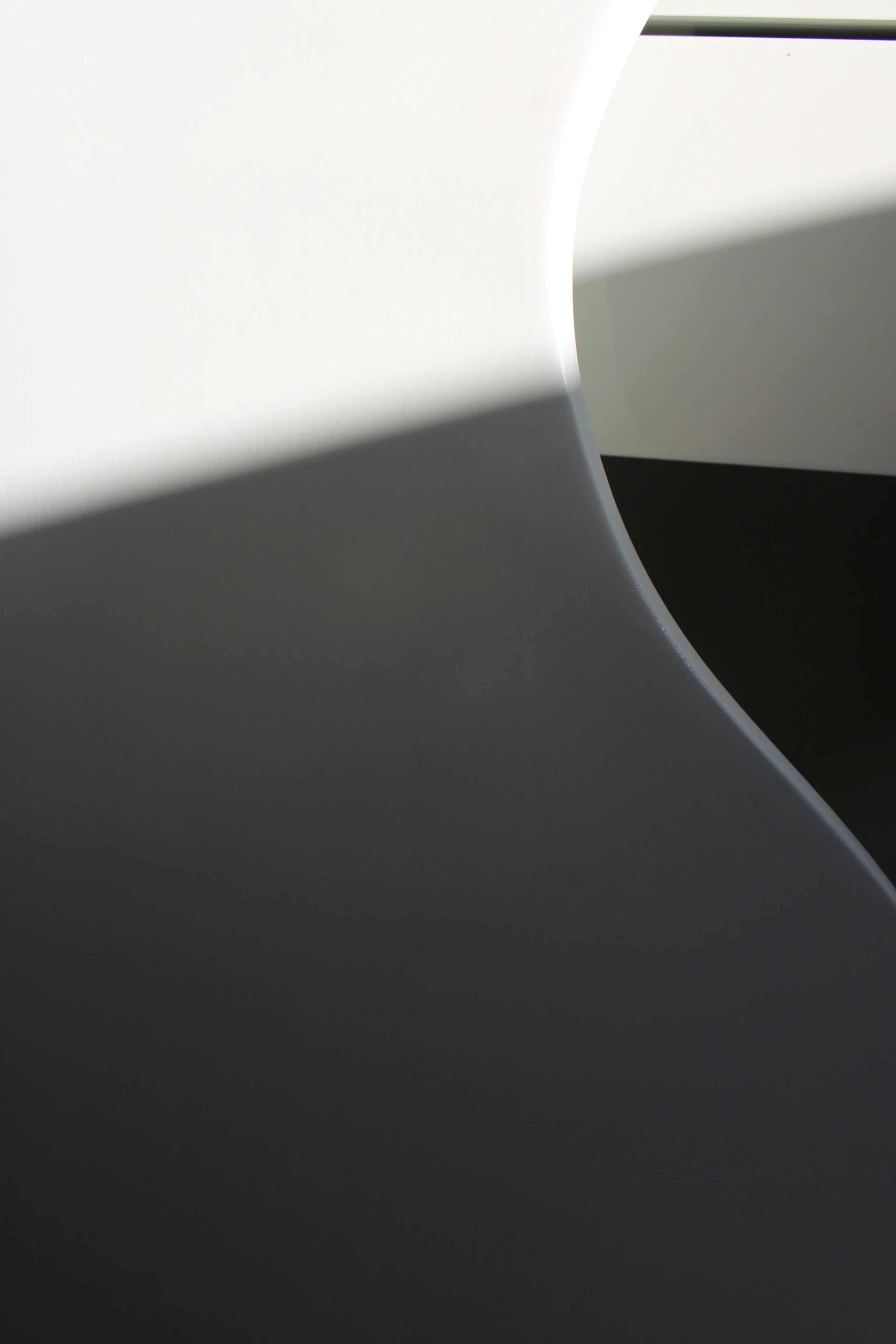 An abstract composition of light and shadow playing across textured surfaces in a grayscale palette.