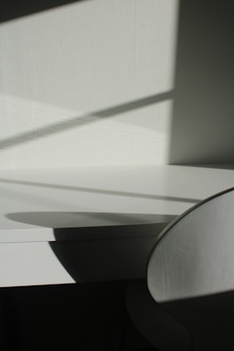 A detailed shot of a geometric 3D printed lamp casting soft shadows on a wooden table.
