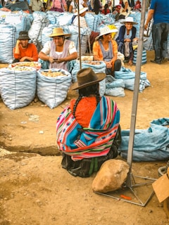 woman in white red and blue stripe shirt sitting on brown sand during daytime