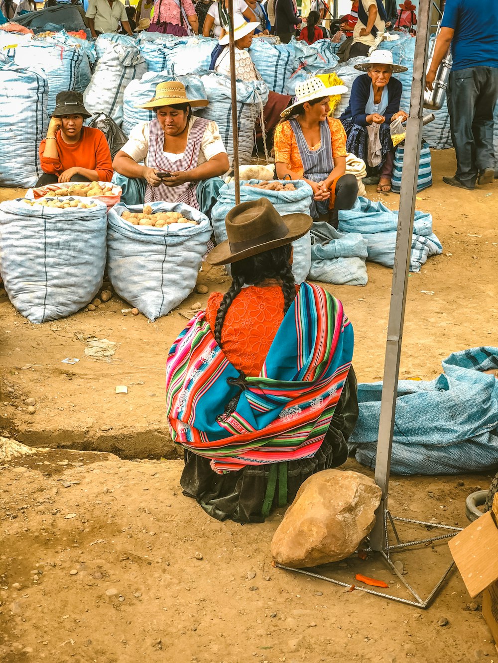 mulher na camisa branca da listra vermelha e azul sentada na areia marrom durante o dia