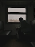 a man sitting on a train looking out the window