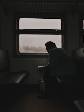 a man sitting on a train looking out the window