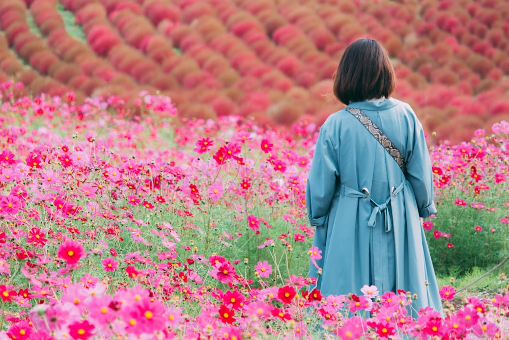 woman in black dress standing on red flower field during daytime