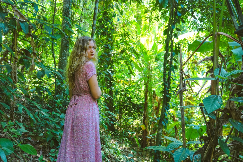 girl in purple dress standing on forest during daytime