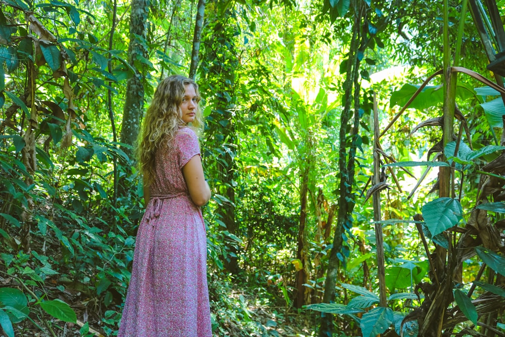 Muchacha en vestido púrpura de pie en el bosque durante el día