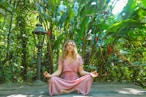 woman in pink dress sitting on wooden pathway