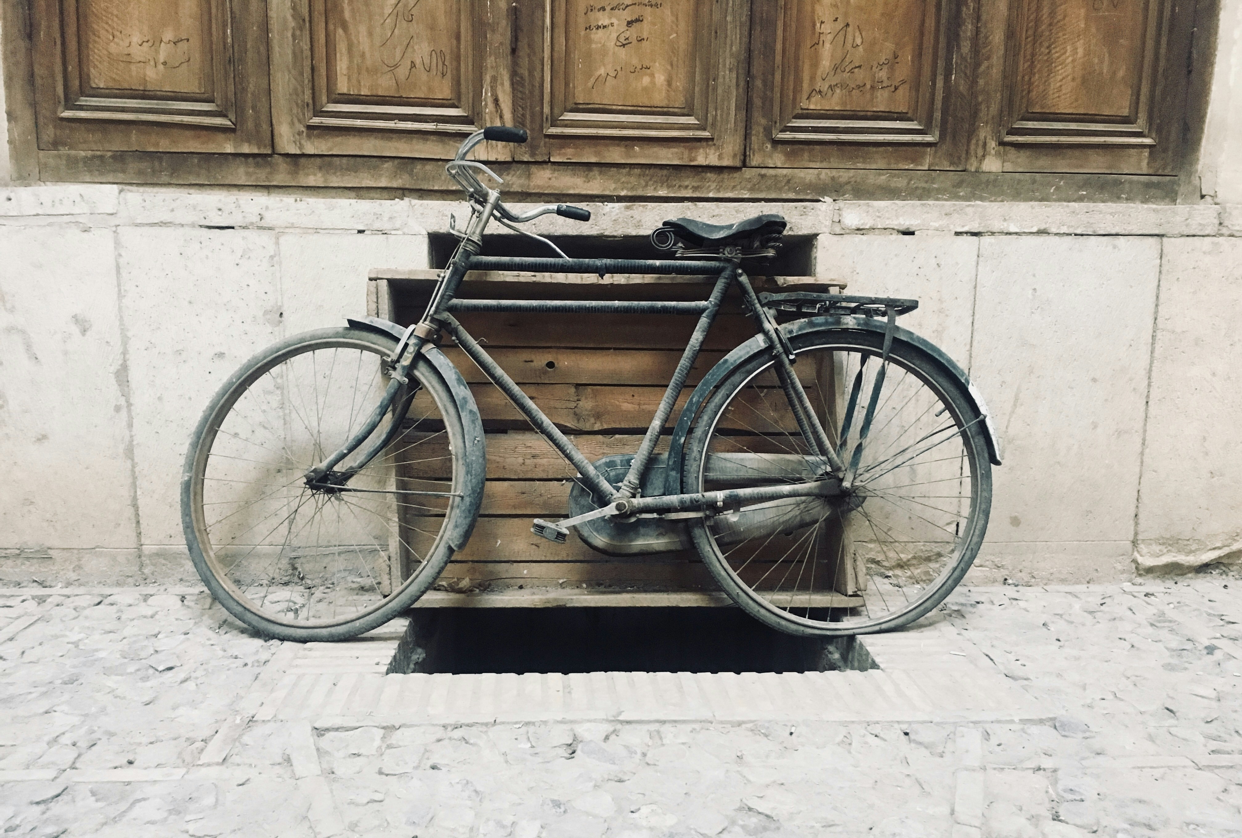 black city bike beside brown wooden wall