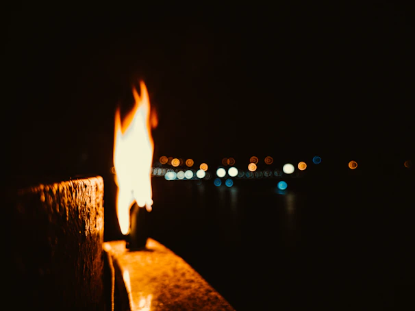 Close-up of a flickering candle casting warm, dancing shadows against a deep navy backdrop.