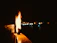 A softly glowing candle flame flickering gently against a desert gold background.