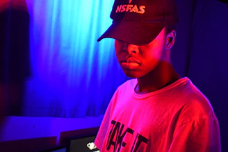 Dynamic shot of a rage cap illuminated by neon red and electric orange lighting with a brutalist backdrop.