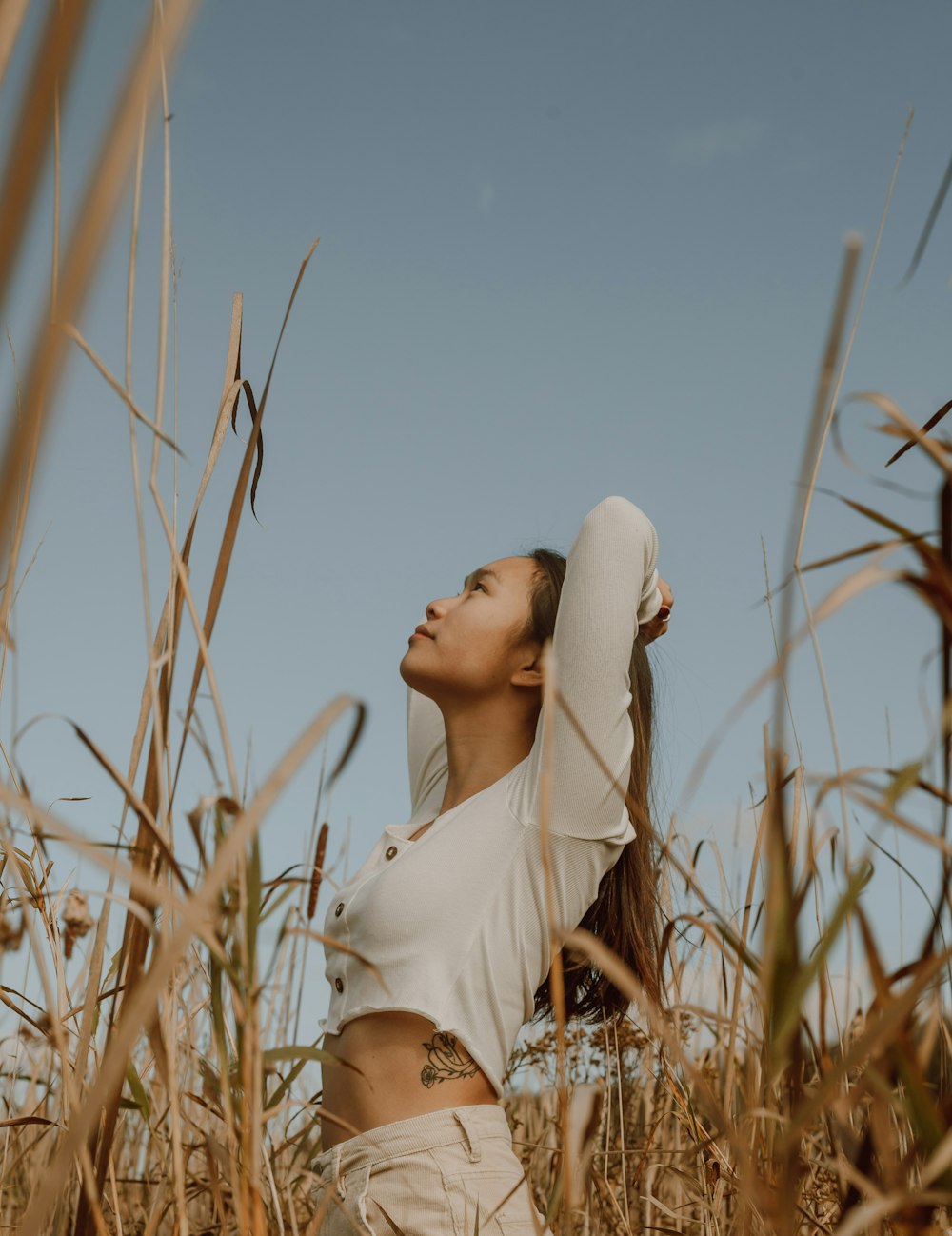 woman in white long sleeve shirt standing on brown grass field during daytime