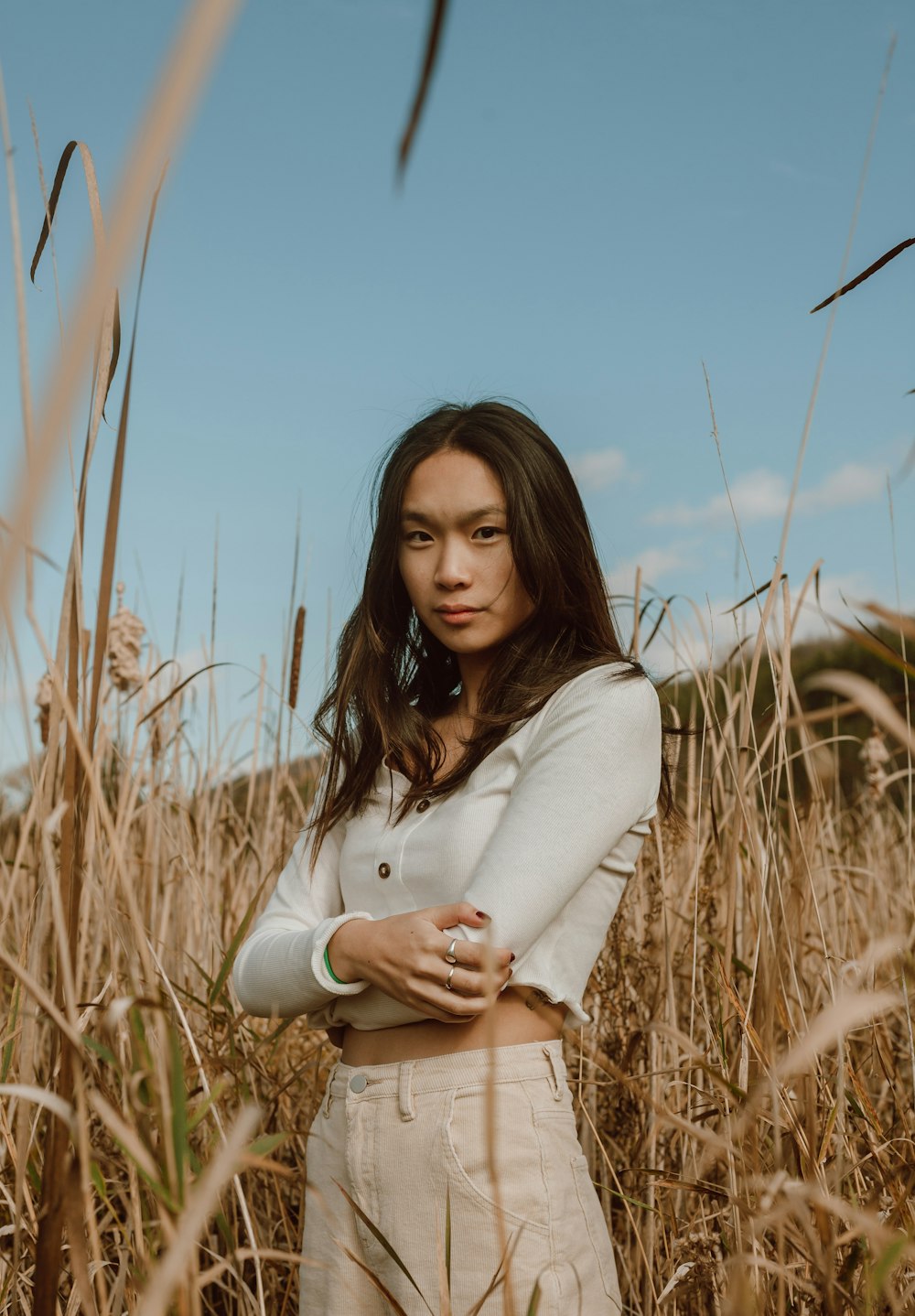 woman in white long sleeve shirt standing on brown grass field during daytime