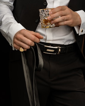 person in white dress shirt and black pants holding gold ring