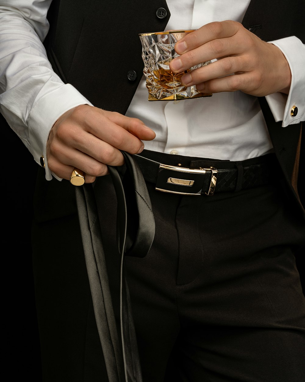 pessoa na camisa social branca e calças pretas segurando o anel de ouro