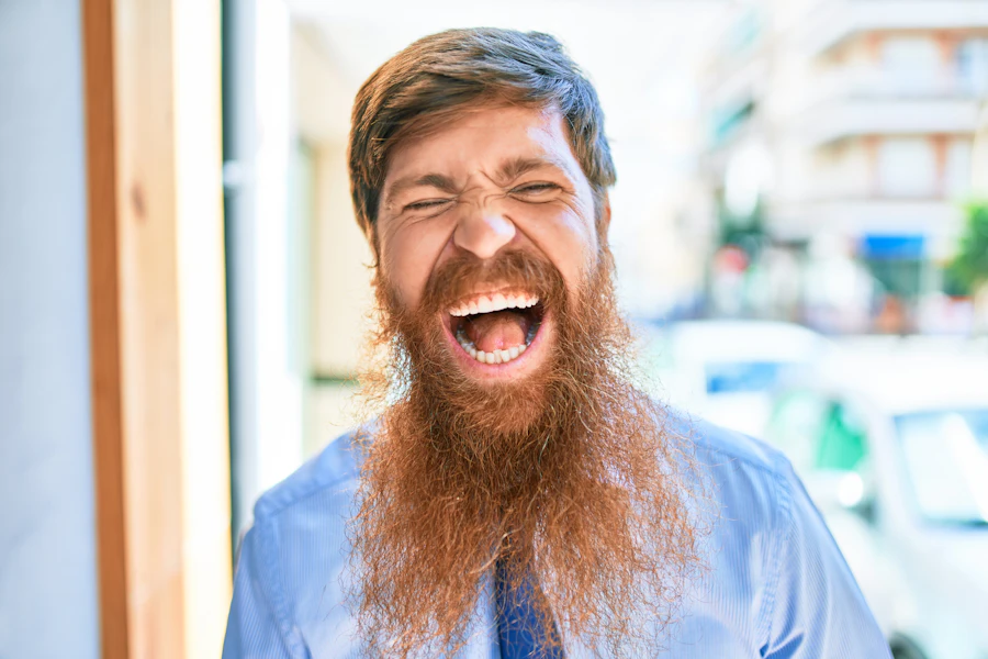 An energetic red-haired man laughing, warm hospitality energy