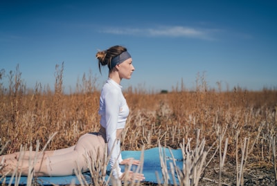 A person practicing yoga outdoors on a vibrant, cushioned yoga mat under a clear sky.