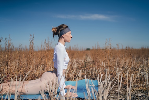 woman in white long sleeve shirt and white pants sitting on blue wooden chair during daytime