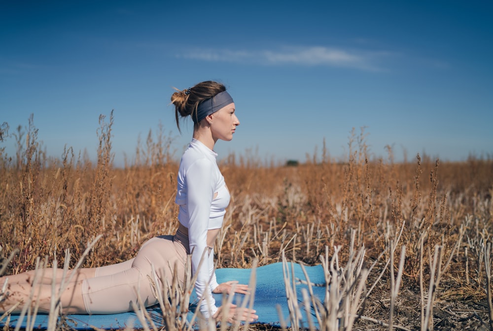 femme en chemise blanche à manches longues et pantalon blanc assise sur une chaise en bois bleue pendant la journée