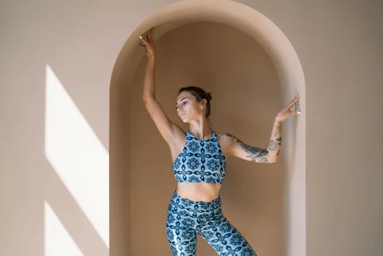 A serene moment of a woman practicing gentle body movement in a sunlit room, embodying feminine energy.