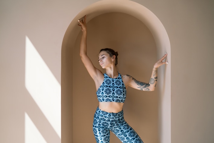Softly lit photo of a serene model wearing breathable, earth-toned yoga leggings in a sunlit studio.