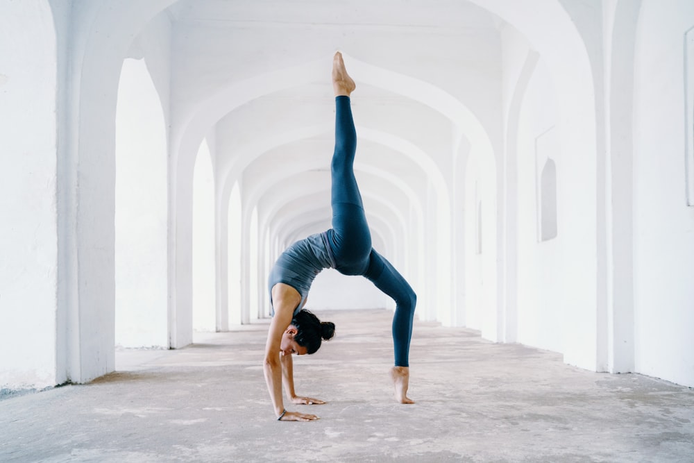 Mujer con leggings azules y camiseta sin mangas negra haciendo yoga