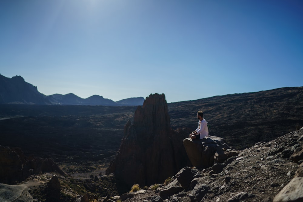 Mujer sentada en la formación rocosa durante el día