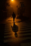 A shadowy figure walking through the foggy streets of London at night.
