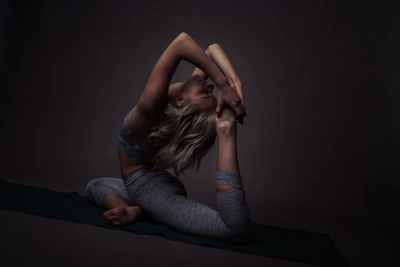 A serene Iyengar yoga practitioner gracefully holding a balanced pose in a softly lit studio with warm beige walls.