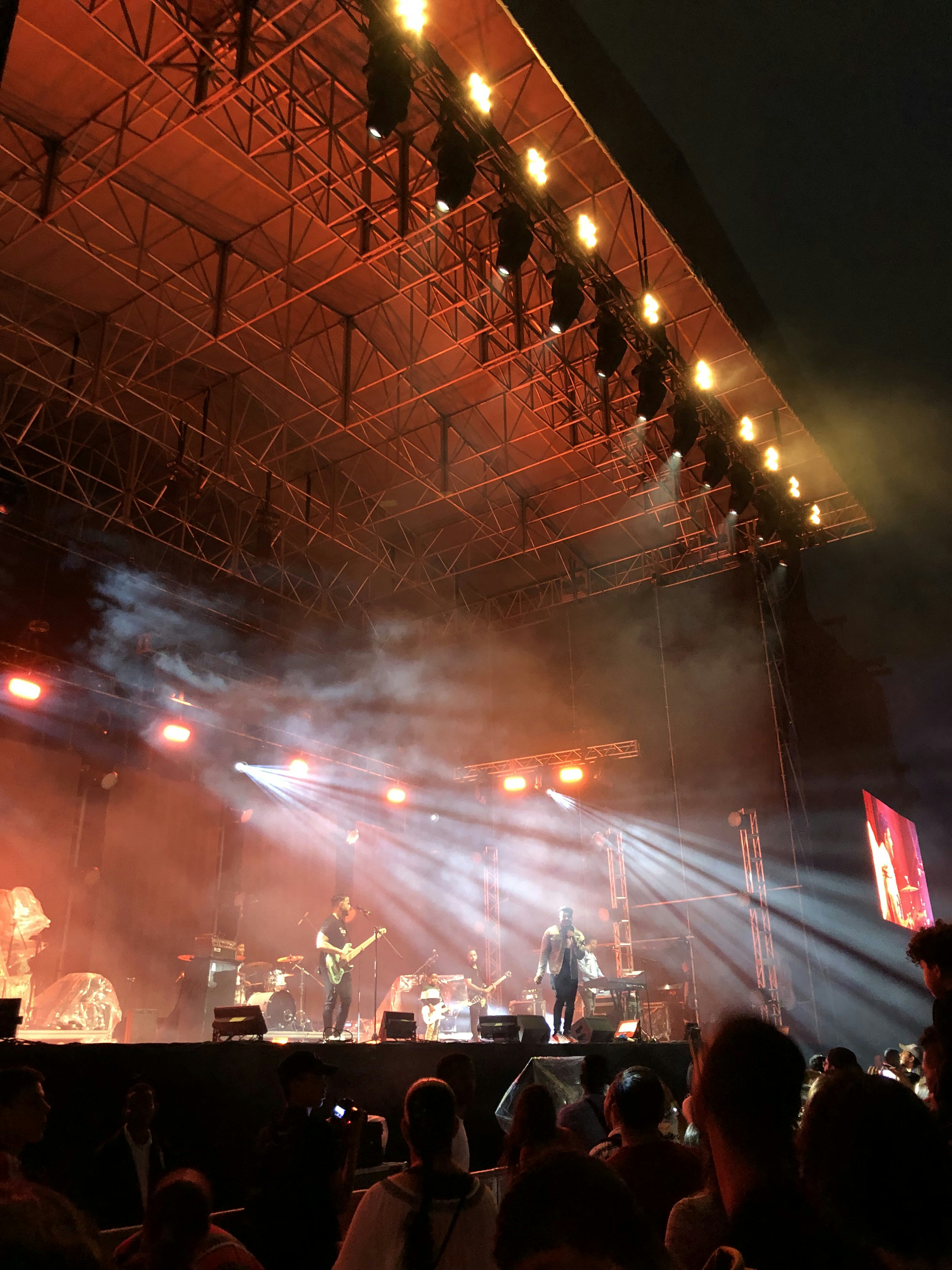 Dramatic dark concert stage with intense blue and white lighting beams piercing smoke