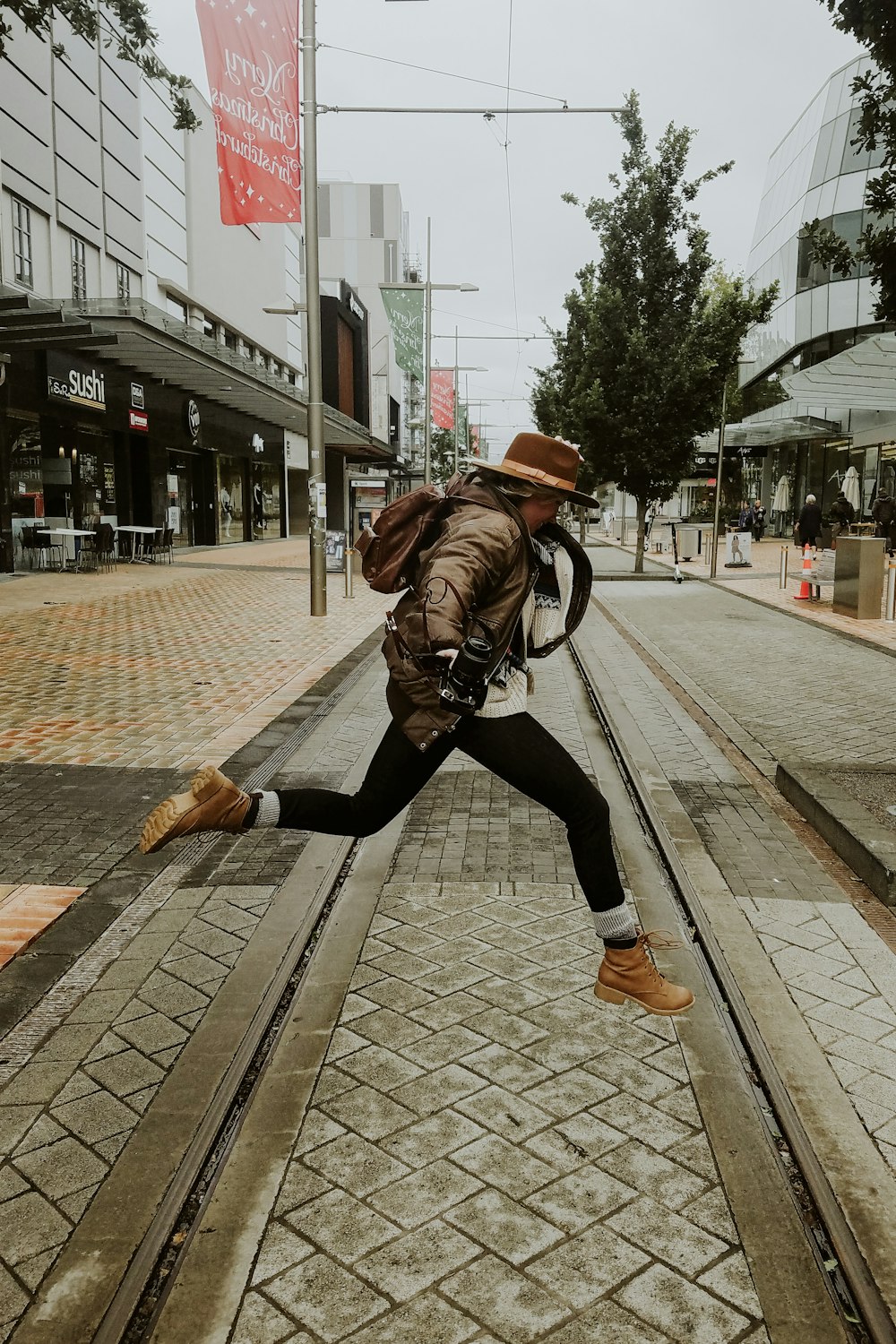 woman in brown leather jacket and black pants walking on sidewalk during daytime