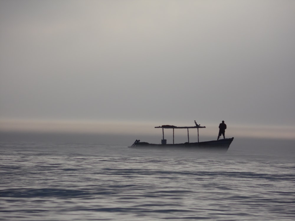 silhouette of person riding on boat on sea during daytime