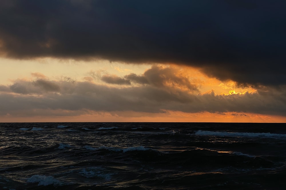 Meereswellen unter bewölktem Himmel bei Sonnenuntergang