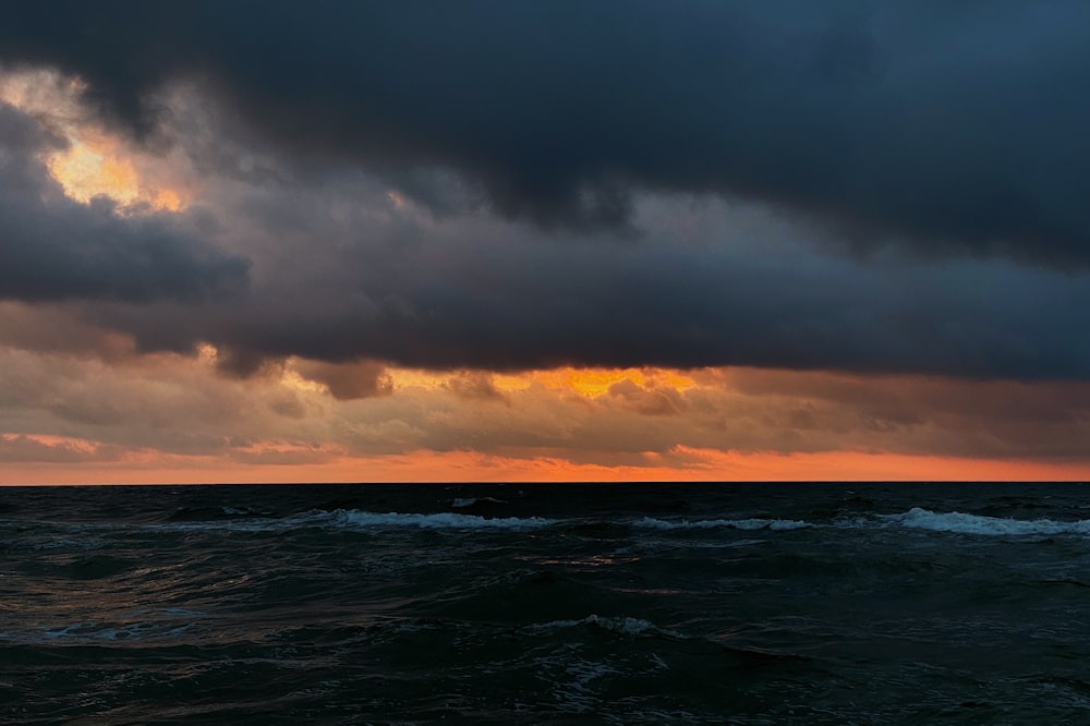 ocean waves under cloudy sky during sunset