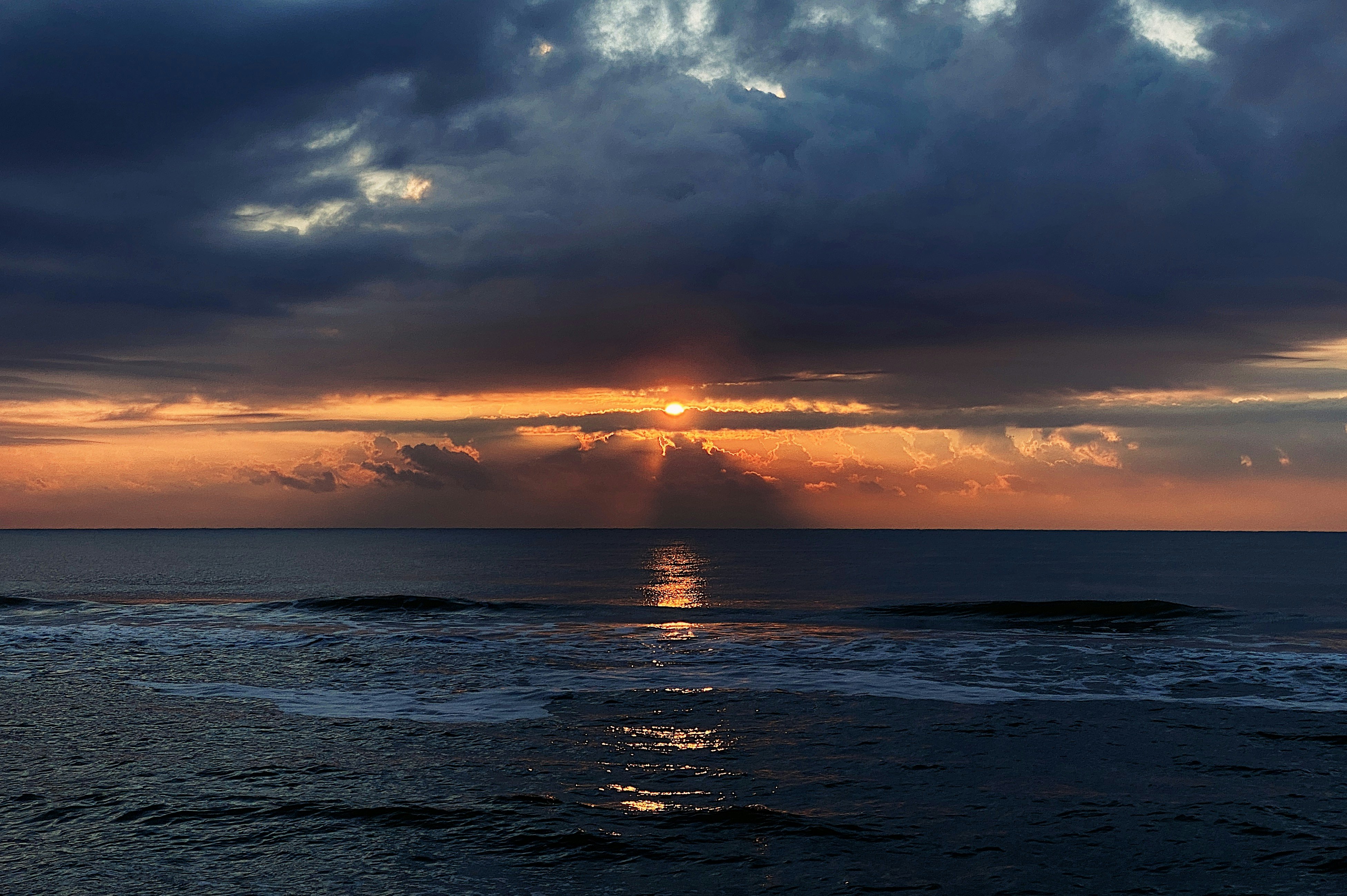 body of water under cloudy sky during sunset