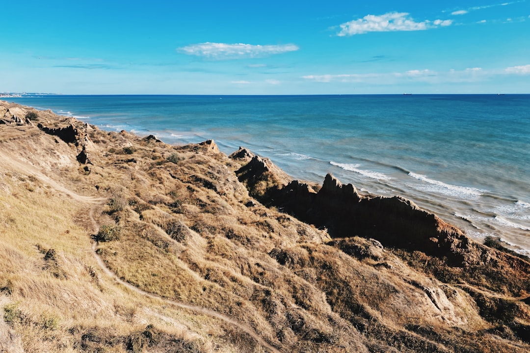 brown rock formation near sea under blue sky during daytime