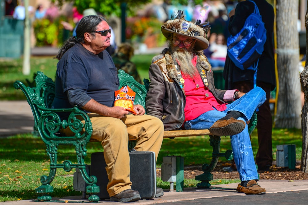 man and woman sitting on green bench during daytime