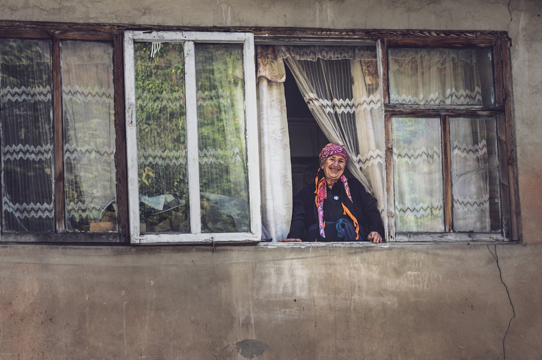 woman in black jacket standing near white wooden framed glass window