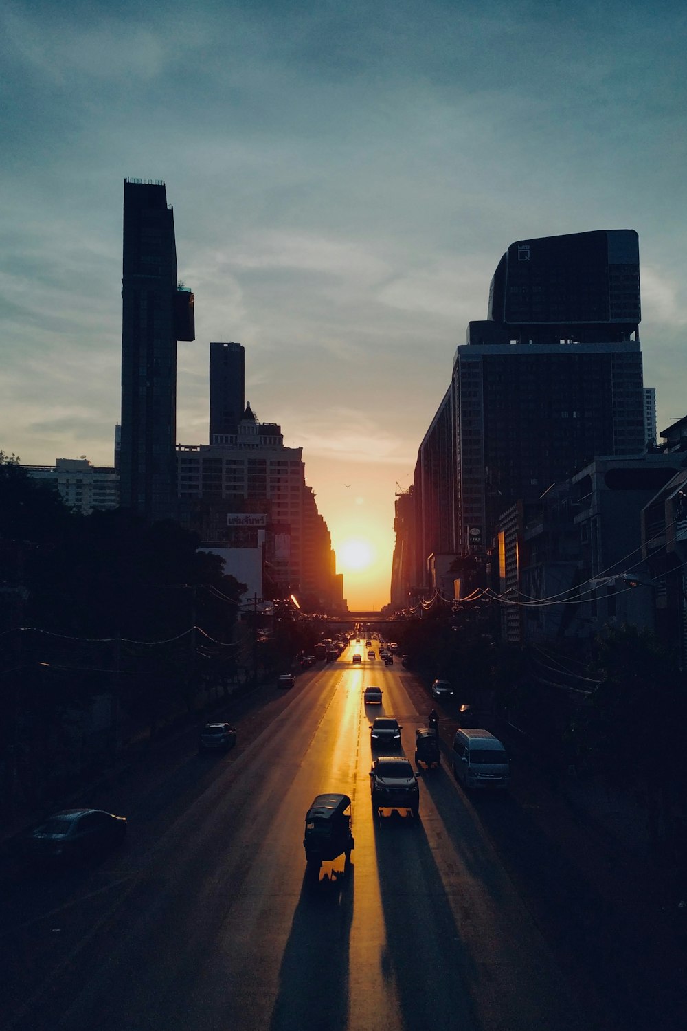 cars on road between high rise buildings during sunset