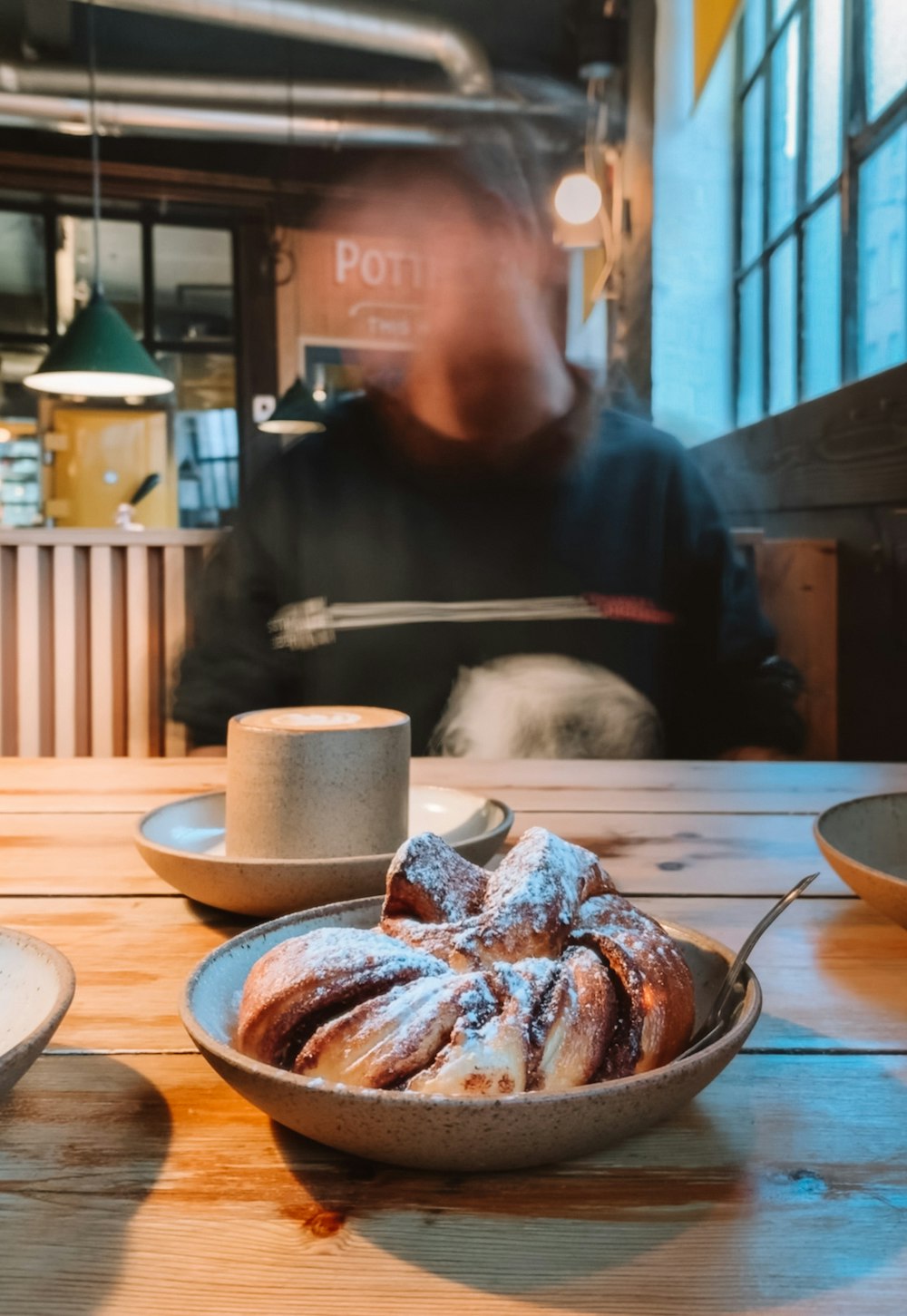 man in black crew neck t-shirt sitting on chair in front of brown wooden table