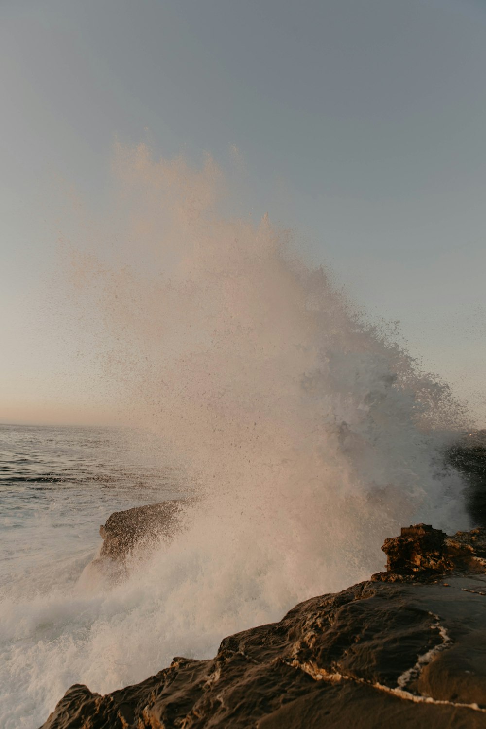 ocean waves crashing on brown rock formation during daytime