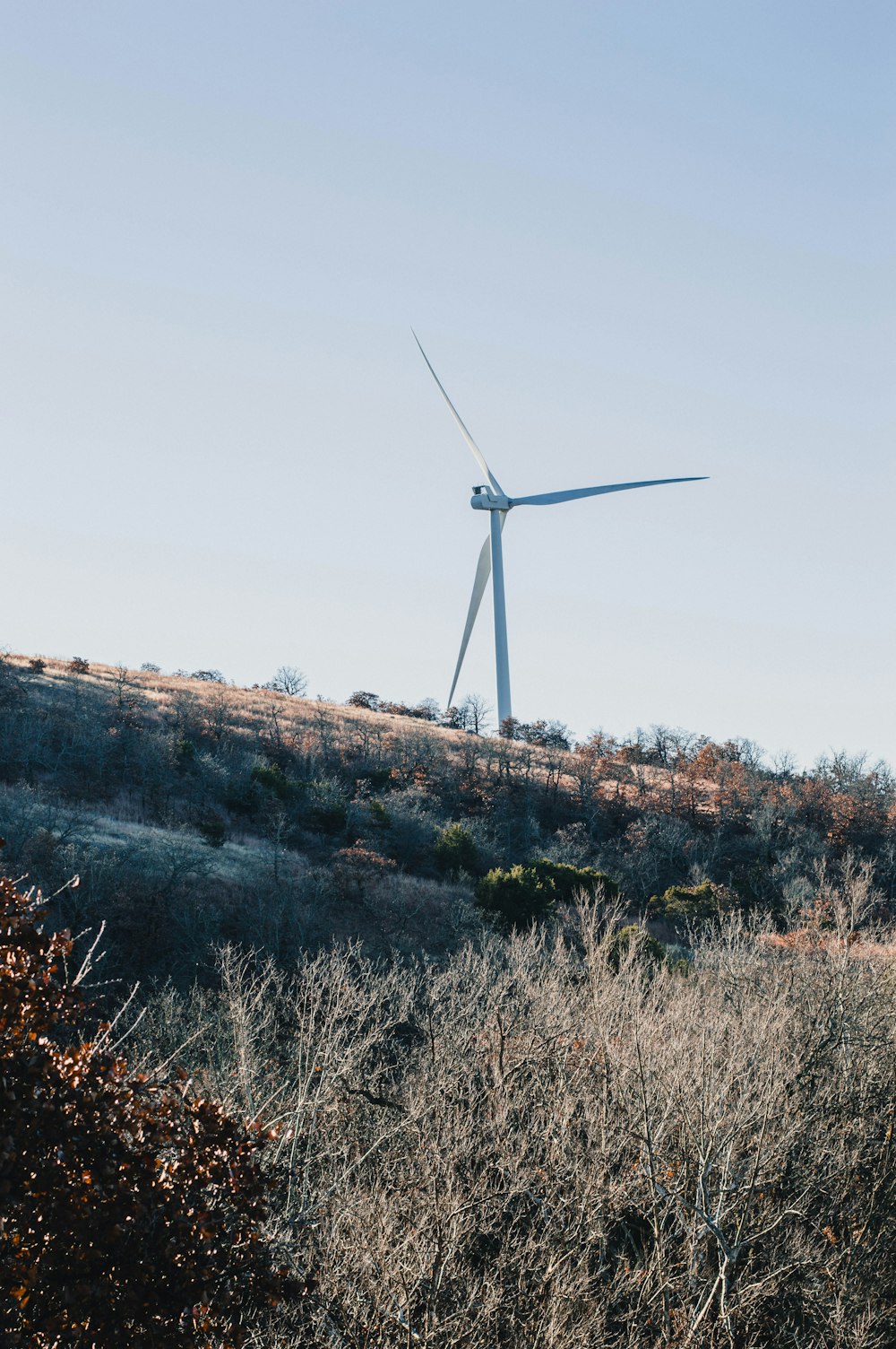 white wind turbine on hill during daytime