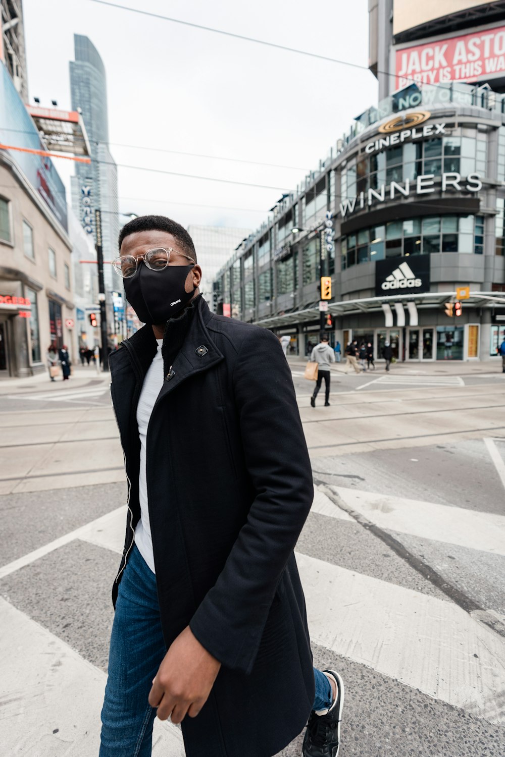 man in black coat standing on sidewalk during daytime