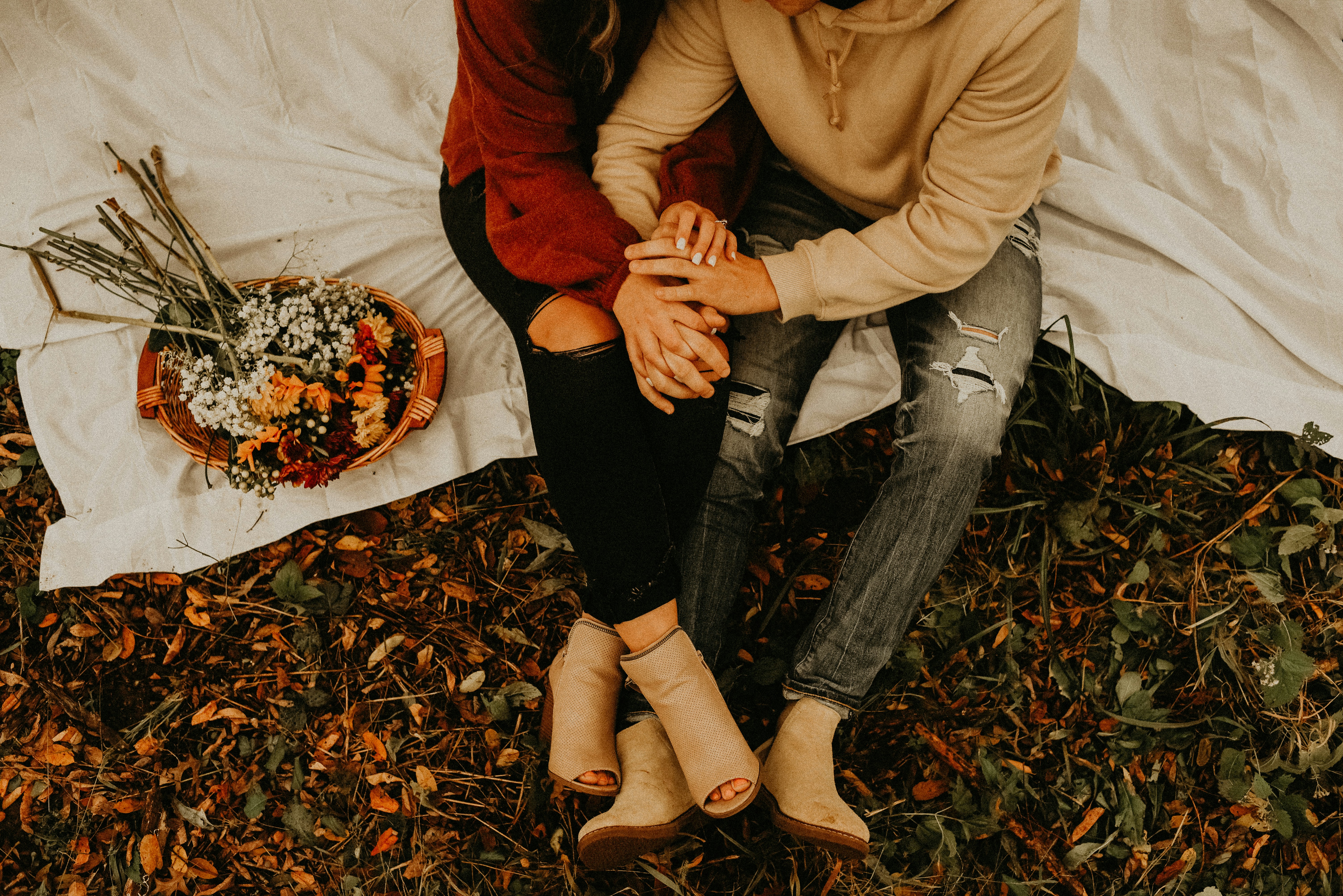 woman-in-brown-coat-and-blue-denim-jeans-sitting-on-ground-with-dried-leaves